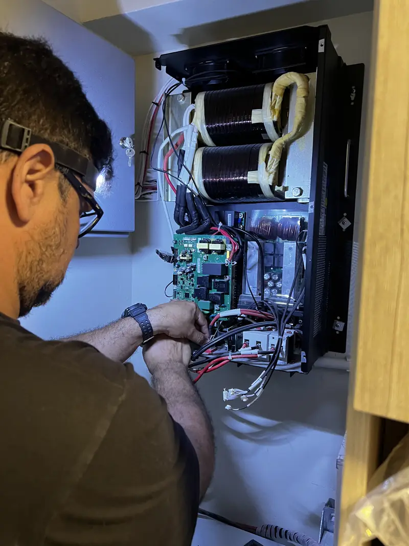 Técnico de Telcom reparando un inversor abierto en el laboratorio